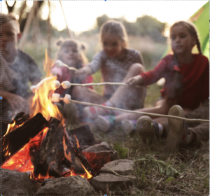 Children roasting marshmallows at summer camp campfire