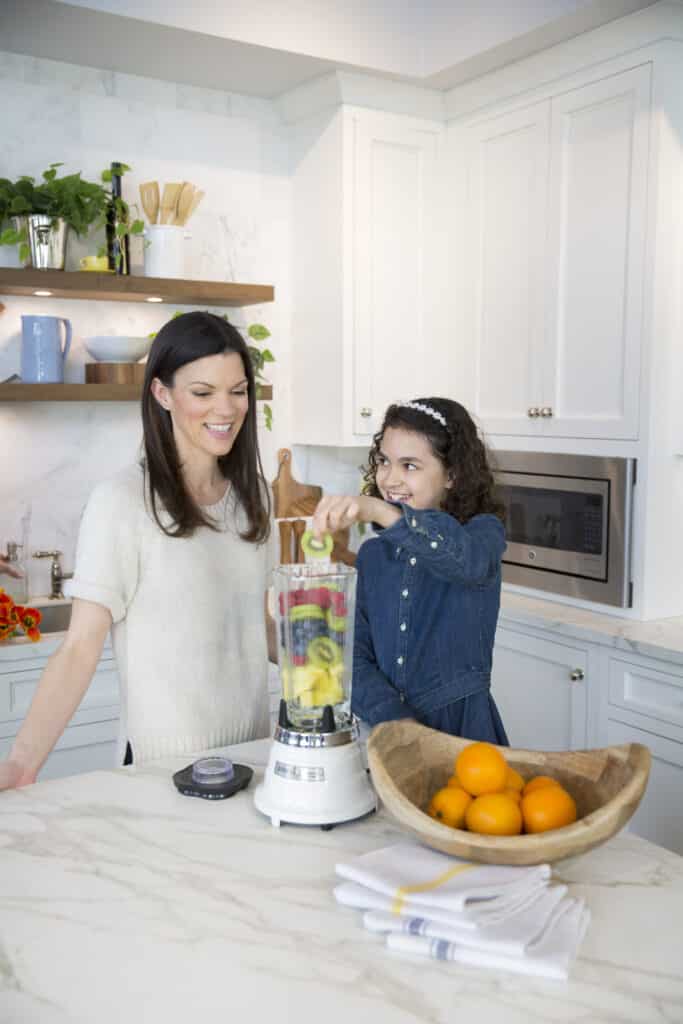 Mother and daughter in the kitchen using a blender while making a smoothie