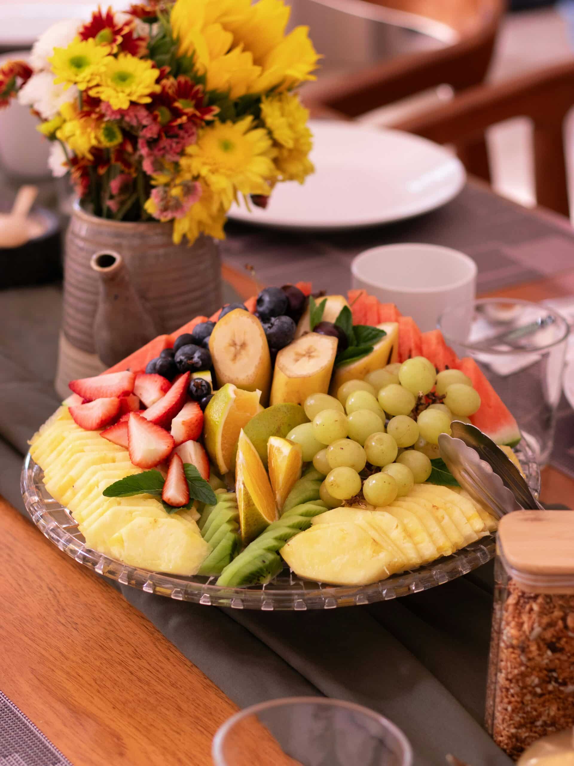 Vibrant fruit platter featuring diverse fruits with floral decoration. Perfect for elegant gatherings.