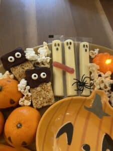 Allergy-friendly spooky charcuterie board with fruit, cookies, rice cakes, popcorn, and Halloween decorations.
