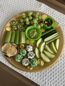 St Patrick's Day allergy friendly charcuterie board with green fruits vegetables cupcakes and chocolate coins