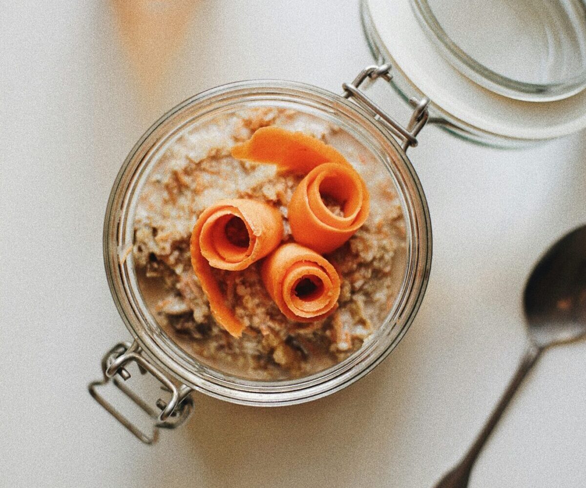 Nut-free carrot cake overnight oats in a jar with grated carrots, raisins, and sunflower seeds