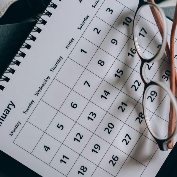 A close-up of a January calendar with eyeglasses on a table, emphasizing planning and organization.